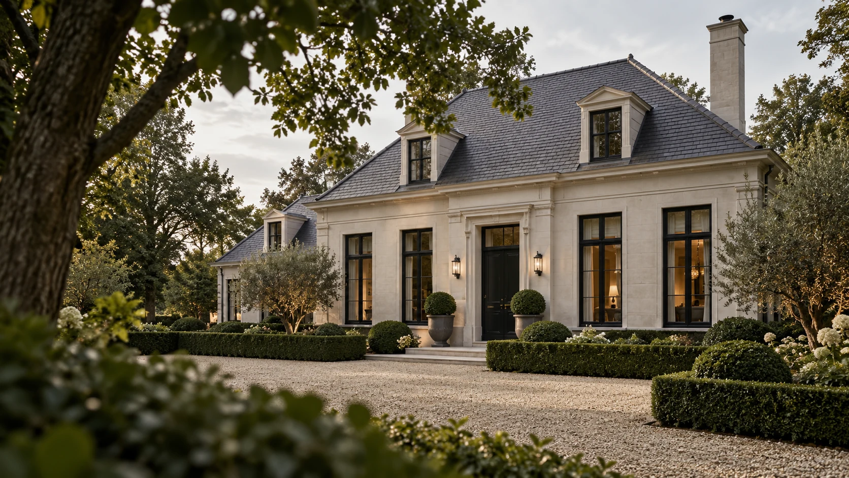 Gerenoveerde klassieke villa met een lichte gevel en donkere kozijnen achter buxushagen